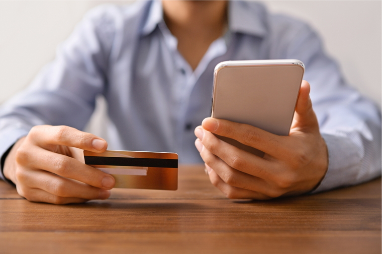 Person mit Handy und Kredit Karte in der Hand