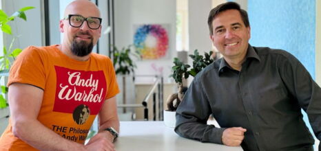 Ronny Büchner und Tino Favetto sitzen nebeneinander und lächeln in die Kamera.