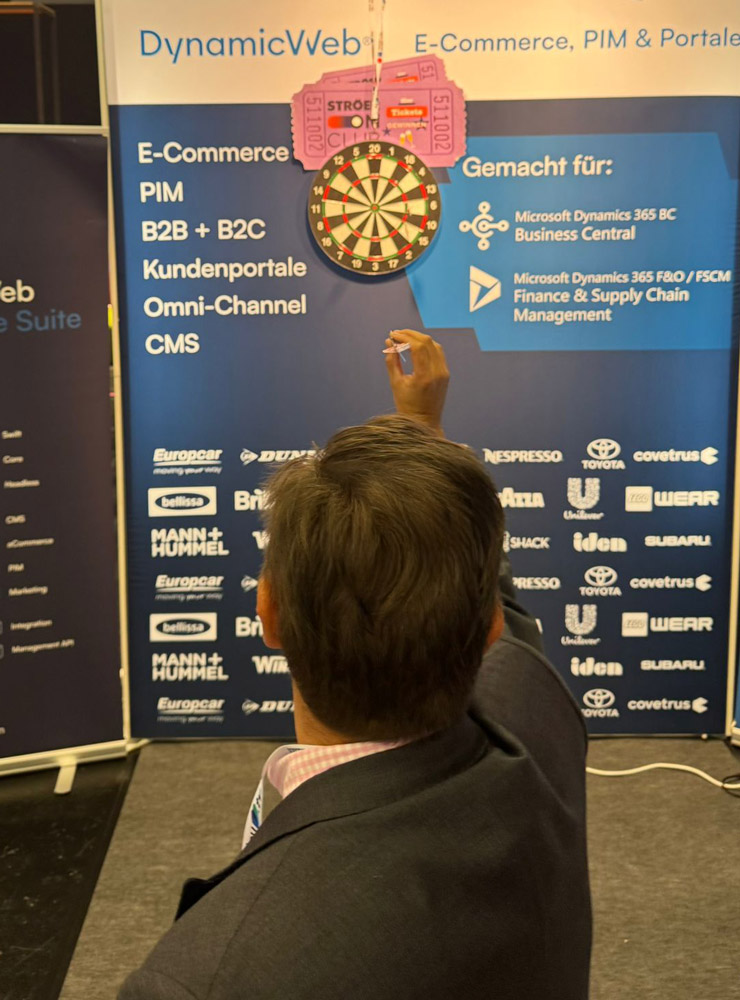 Mann wirft Dartpfeil auf Dartscheibe am DynamicWeb Stand